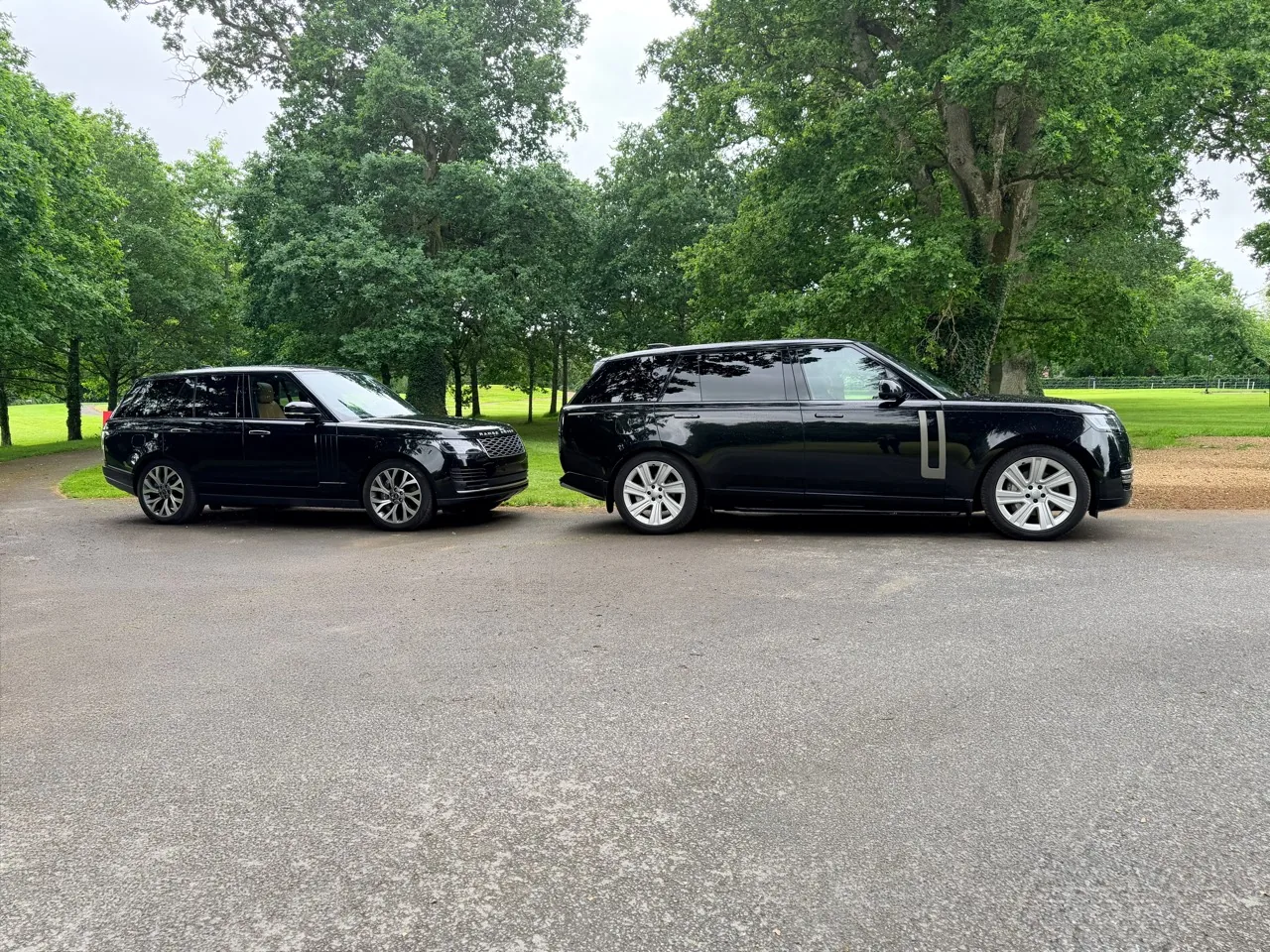 Two black Range Rovers parked on a tree-lined drive